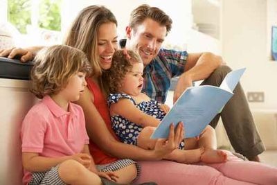 Parents Sitting With Children Reading Story Indoors